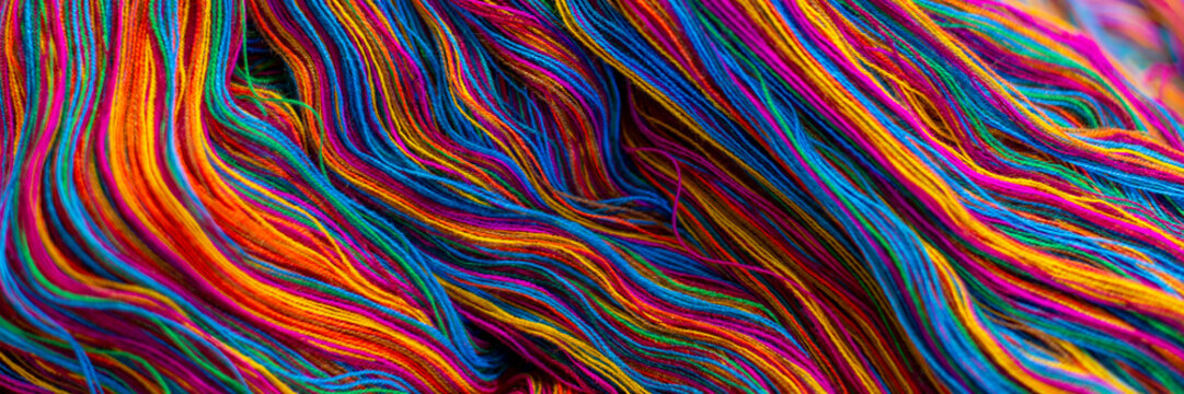 Colorful waves of vibrant, mixed rainbow colours of cotton thread, ready to be woven into traditional Guatemalan textiles. Abstract, fashion and travel, background texture banner. 