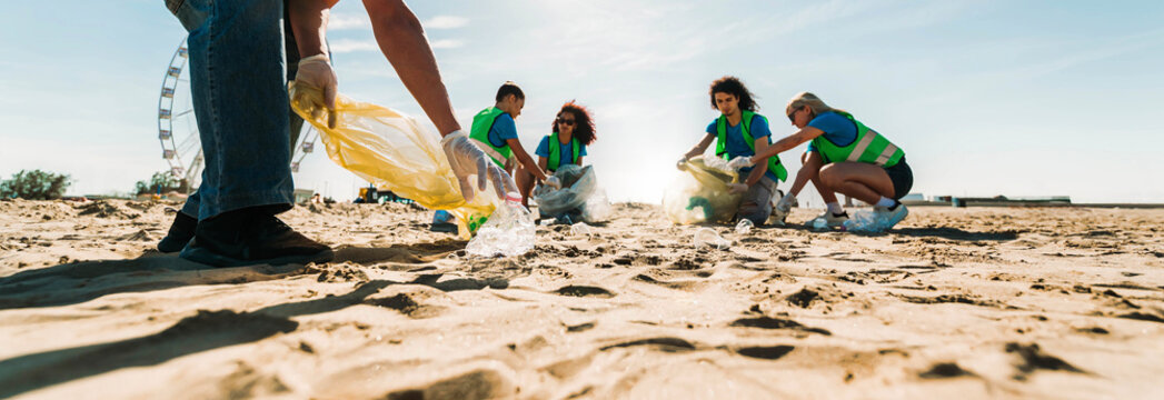 Group of eco volunteers picking up plastic trash on the beach - Activist people collecting garbage protecting the planet - Ocean pollution, environmental conservation and ecology concept