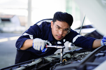 Portrait of an Asian mechanic checking the safety of a car. Maintenance of damaged parts in the...