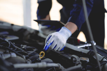 Auto mechanic checking oil in car engine Technician inspects and maintains car engines.