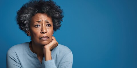 Blue background sad black American independent powerful Woman. Portrait of older mid-aged person...