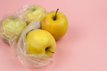 A bag of apples is sitting on a pink background