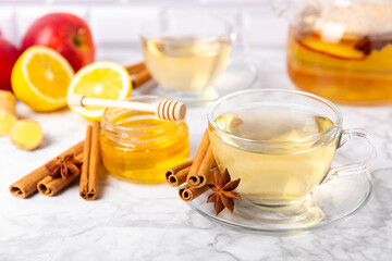 Fragrant hot tea with cinnamon stick and anise on a textured wooden background. A cup of hot tea with honey, lemon, mint and apples. Spicy tea with spices. Immunity tea. Health concept.Copy space.