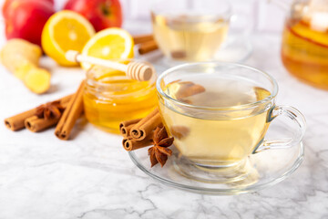 Fragrant hot tea with cinnamon stick and anise on a textured wooden background. A cup of hot tea with honey, lemon, mint and apples. Spicy tea with spices. Immunity tea. Health concept.Copy space.