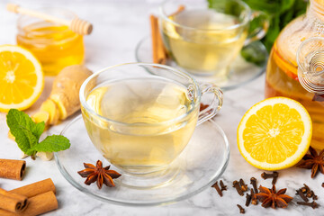 Fragrant hot tea with cinnamon stick and anise on a textured wooden background. A cup of hot tea with honey, lemon, mint and apples. Spicy tea with spices. Immunity tea. Health concept.Copy space.