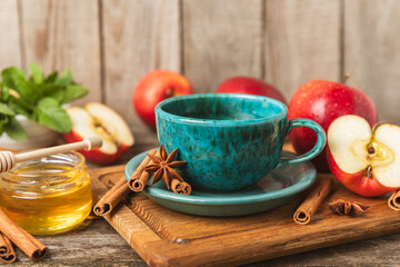 Fragrant hot tea with cinnamon stick and anise on a textured wooden background. A cup of hot tea with honey, lemon, mint and apples. Spicy tea with spices. Immunity tea. Health concept.Copy space.
