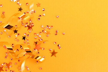 Glowing golden ribbons, stars and crystals confetti on a yellow background. Festive composition...