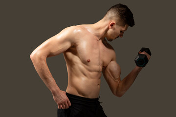 A man is holding a dumbbell in his hands, showcasing strength and fitness training. Mans muscles...