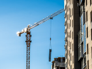 A tall tower crane on the construction of urban buildings.