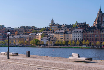 Obraz premium The block Mariaberget in the district Södermalm a pier with bench at the bay Riddarfjärden, a sunny summer day in Stockholm