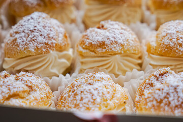 Cream puffs filled with pastry cream and sprinkled with powdered sugar.  Close up.