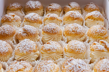 Cream puffs filled with pastry cream and sprinkled with powdered sugar.  Close up.