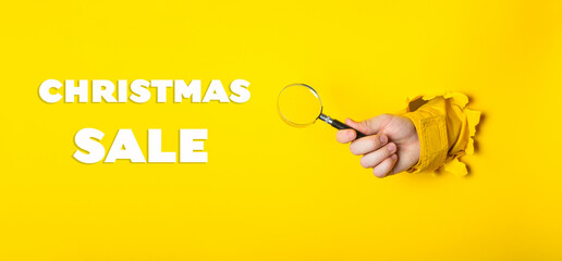 A person holding a magnifying glass with the words Christmas Sale written below