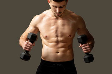 A man is standing and holding two dumbbells in his hands, showing strength and fitness. He has a...