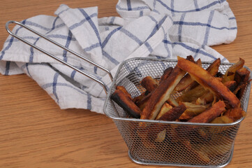 Panier de frites avec un torchon en gros plan sur fond en bois