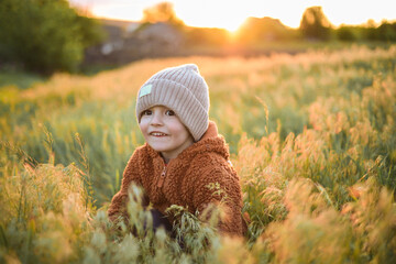 A little baby running on the grass at sunset and enjoying life. A game of catch-up with a toddler. Fun and activities for children on the street. Happy childhood.