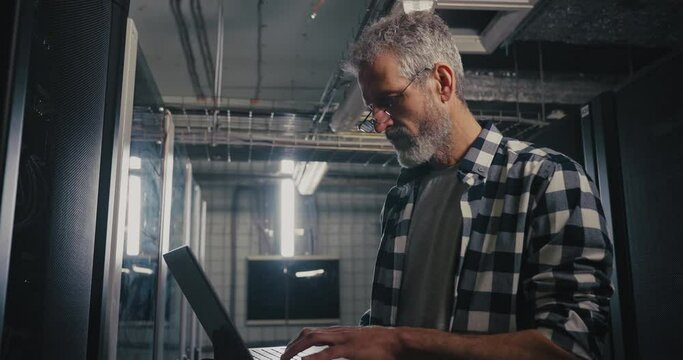 Man Working on Laptop in Server Room