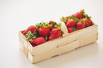 Strawberries in a wooden basket and on a white background. Juicy fresh strawberries. 