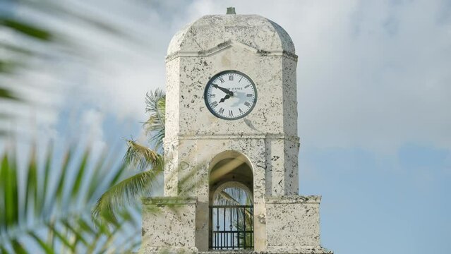 Front view of Worth Avenue Clock Tower located in Palm Beach, Florida. Architectural monument of historical design with weathered white facade with Roman numerals