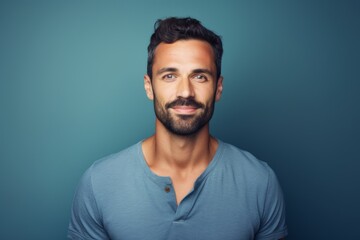 Obraz premium Portrait of a cheerful man in his 30s smiling at the camera in front of blank studio backdrop