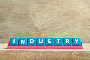 Tile letter on red rack in word industry on wood background