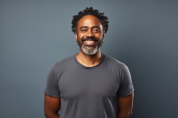 Obraz premium Portrait of a joyful afro-american man in his 40s smiling at the camera on blank studio backdrop