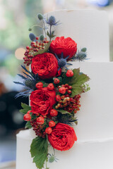 the cake is covered with white cream icing and decorated with a red flower, which is served on the table