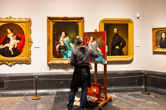 Prado Museum, Madrid, Spain - April 24 2024: A painter painting by copying another painting inside the museum