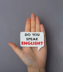 A hand holding a sign that says Do you speak English