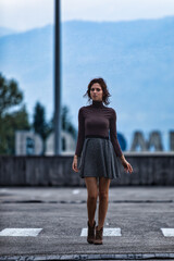 Young woman stands contemplatively on an empty road