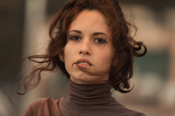 Young woman with wind-tousled hair, thoughtful gaze