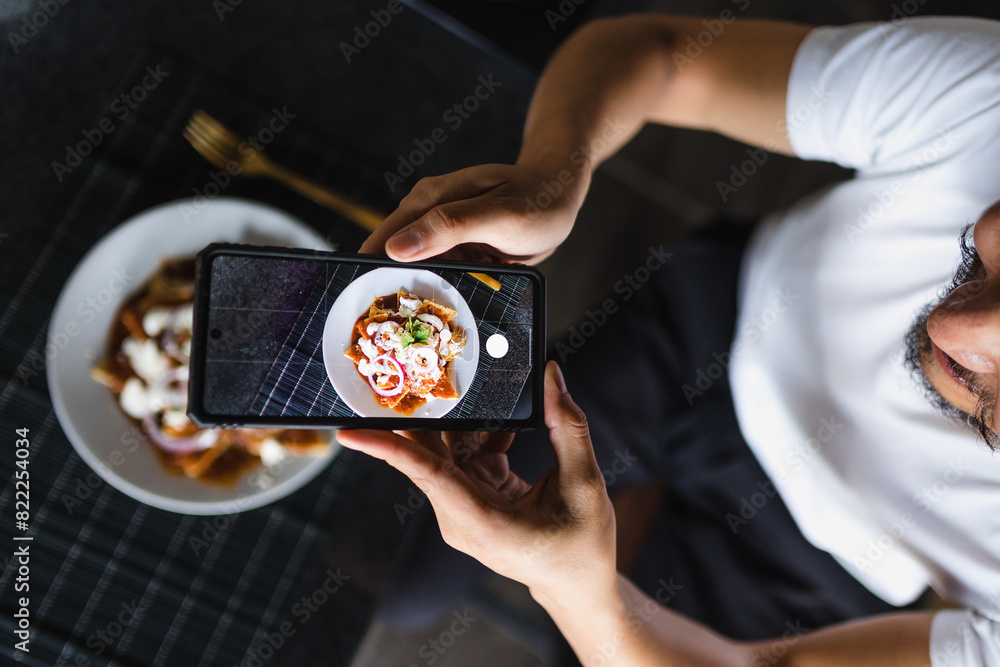 Wall mural latin man using smartphone to take photos of food on the table at home in Mexico Latin America - Wall murals