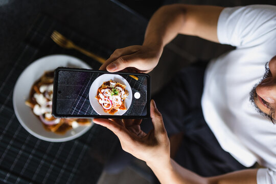 latin man using smartphone to take photos of food on the table at home in Mexico Latin America - Powered by Adobe