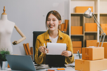 Asian SME business women use laptop computer checking customer order online shipping boxes at home....