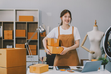 Asian SME business women use laptop computer checking customer order online shipping boxes at home....