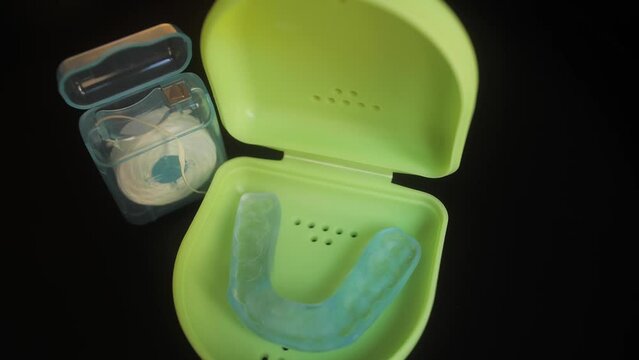 Case with mouthguard for teeth and dental floss close up. Dental care concept.