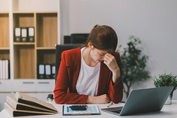 Asian women sitting in a home office With stress and eye strain.Tired businesswoman holding...