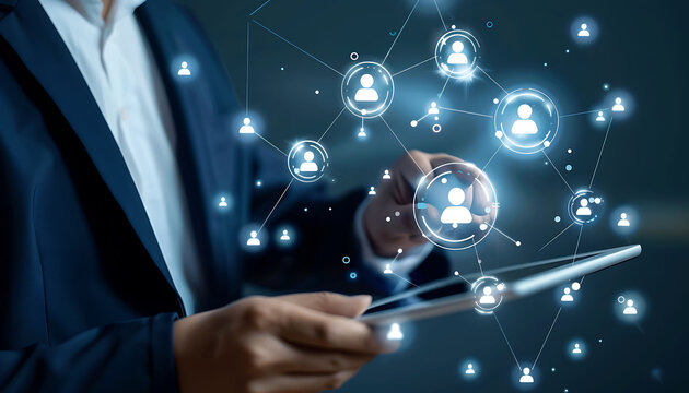 A businessman using a digital tablet to engage with a virtual network of customer and HR icons, demonstrating advanced technology for CRM and recruitment