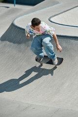 Young skater boy rides skateboard up ramp in vibrant outdoor skate park on a sunny summer day.