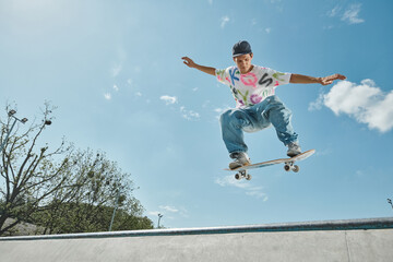 A young skater boy defies gravity, soaring through the air on his skateboard in a sunny skate park.