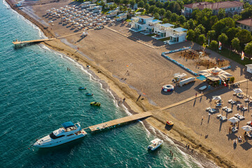 A scenic aerial view of a beachfront. The turquoise sea which is calm and clear, with several boats...