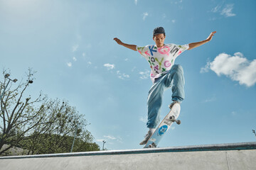 A young skater boy confidently rides his skateboard up a steep ramp in a skate park on a sunny...