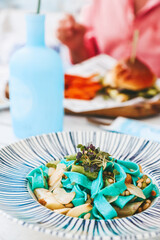 Close-up colorful vegetarian blue pasta, garnished with asparagus, pine nuts, and fresh greens
