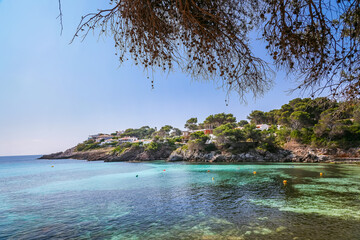 Font de Sa Cala beach in Mallorca offers a peaceful view of clear turquoise waters, rocky outcrops,...