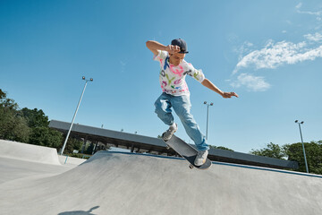 A young man confidently skateboards down the side of a ramp in a sunny outdoor skate park, showing his skill and passion for the sport. © LIGHTFIELD STUDIOS