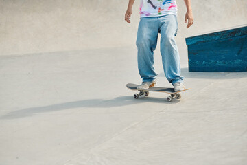 A young skater boy riding a skateboard down a cement ramp in a vibrant outdoor skate park on a sunny summer day.