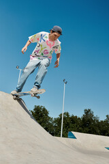 A young skater boy rides a skateboard down the ramp at an outdoor skate park on a sunny summer day.