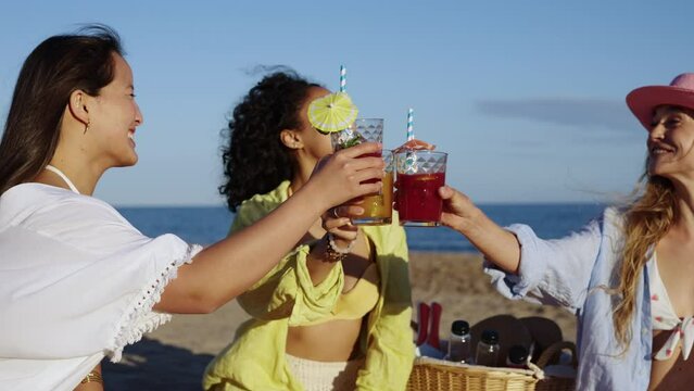 Three women are sitting on the beach, smiling and enjoying each other's company