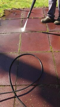 Man cleaning stone garden paths with high pressure power washer. Rubber-coated platform washing. Vertical video. Taken from hand. High quality 4k footage