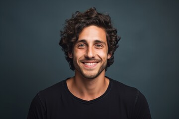 Fototapeta premium Portrait of a grinning man in his 20s smiling at the camera in blank studio backdrop